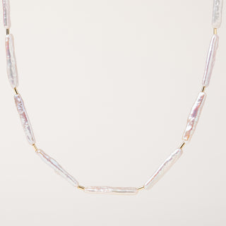 Collana con perle d'acqua dolce allungate e dettagli in oro su sfondo neutro