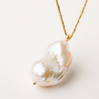 Collana dorata lunga con un pendente in rara perla keshi dalle forme irregolari.