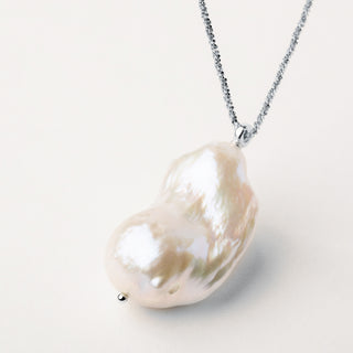 Collana dorata lunga con un pendente in rara perla keshi dalle forme irregolari.