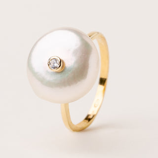 Anello dal design aperto con una perla d'acqua dolce da una parte e uno zircone dall'altra.