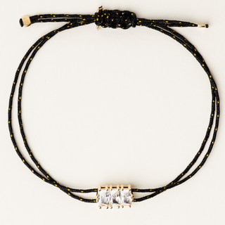 Bracciale a filo regolabile con elemento centrale dorato e zirconi lineari.