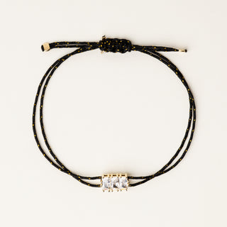 Bracciale a filo regolabile con elemento centrale dorato e zirconi lineari.